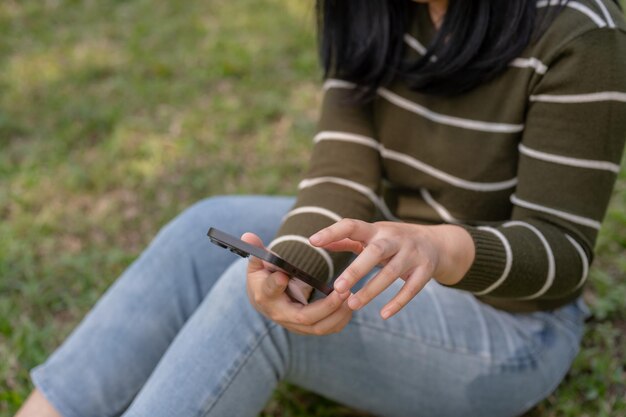 Een vrouw chat met haar smartphone met haar vrienden terwijl ze zich ontspant in een park