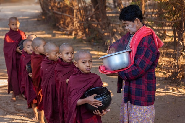 Een vrouw deelt aalmoezen uit aan boeddhistische beginners. Myanmar