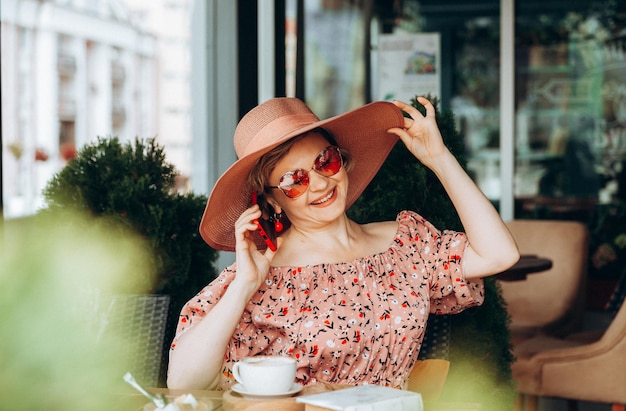 Een vrouw die aan de telefoon praat Een vrouw met een mobiele telefoon zit in een café een vrouw in een jurk en een hoed in een café