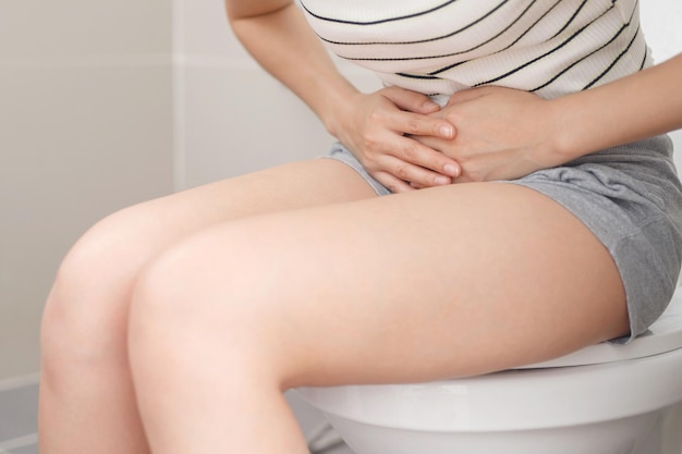 Een vrouw die diarree thuis in de badkamer uitscheidt