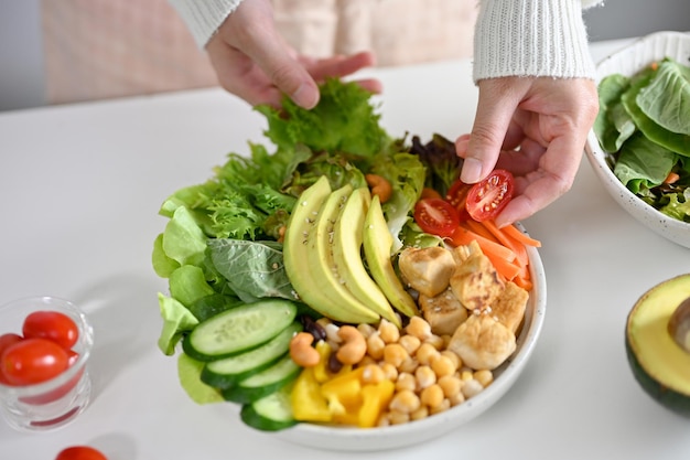 Een vrouw die een bord met Boeddha-kom of plantaardige saladegroenten maakt