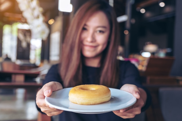 Een vrouw die een bord met donut vasthoudt en toont