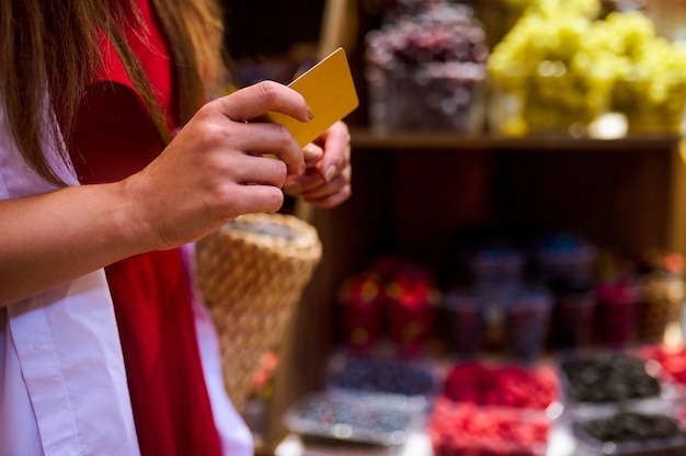 Een vrouw die een creditcard in haar handen houdt terwijl ze in een winkel voor fruit betaalt