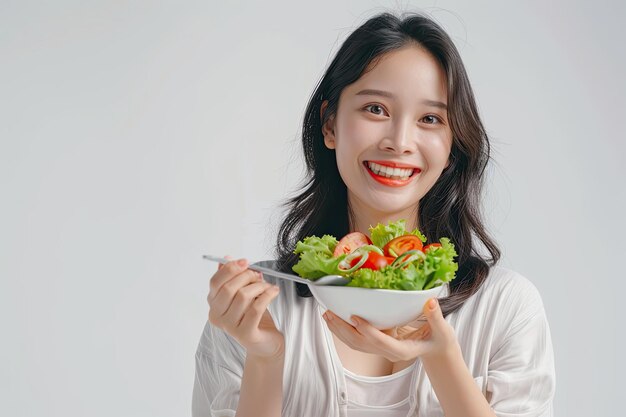 een vrouw die een kom salade vasthoudt met een schaal salade