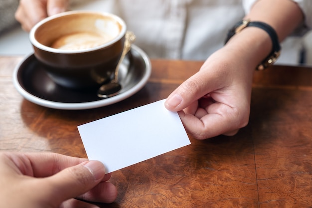 Een vrouw die een leeg visitekaartje vasthoudt en aan iemand geeft