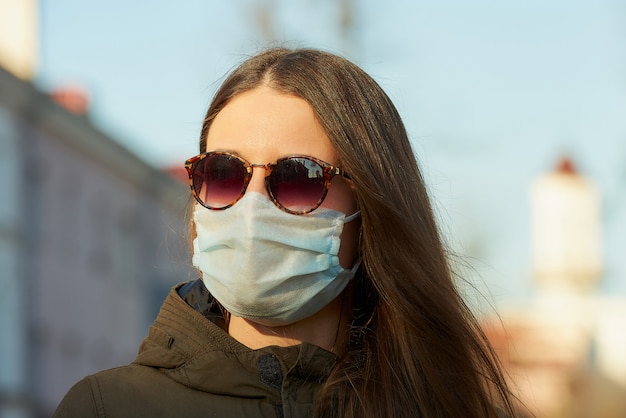 Een vrouw die een medisch gezichtsmasker draagt om het verspreide coronavirus op een stadsstraat bij zonsondergang te vermijden