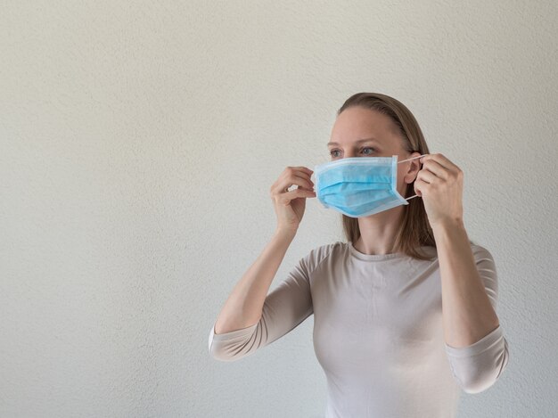 Een vrouw die een medisch wegwerpmasker opzet om besmettelijke virussen te voorkomen