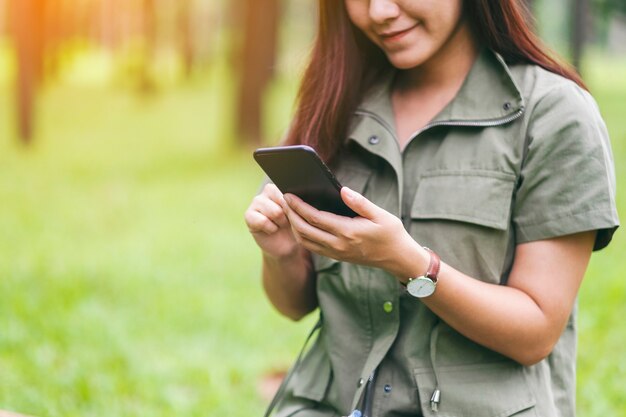 Een vrouw die een mobiele telefoon vasthoudt en gebruikt in het park