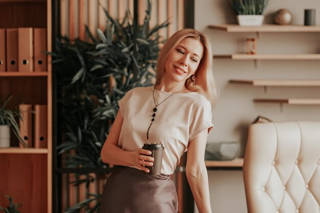 Een vrouw die een pauze heeft en ontspannen op kantoor staat en koffie drinkt