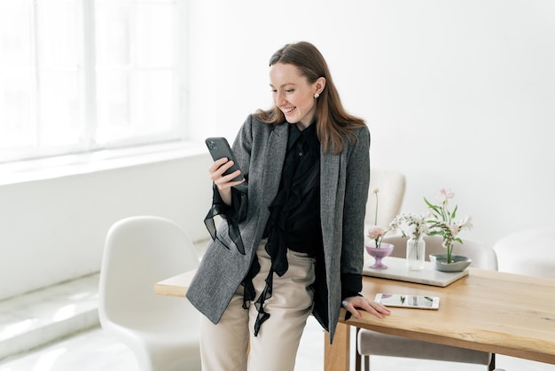 Een vrouw die een telefoon in haar handen gebruikt en een bericht typt in een chat Een persoon op kantoor tijdens