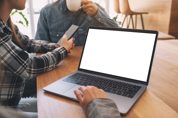 Een vrouw die en op mockuplaptopcomputer touchpad met collega's in vergadering gebruiken raken