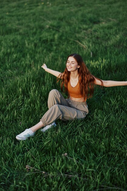 Foto een vrouw die geniet van het buitenleven in het park op het groene gras in vrijetijdskleding met lang golvend haar verlicht door de felle zomerzon zonder muggen