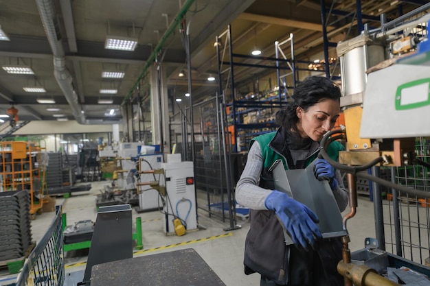 Foto een vrouw die in een moderne metaalfabriek werkt, assembleert onderdelen voor een nieuwe machine. hoge kwaliteit foto