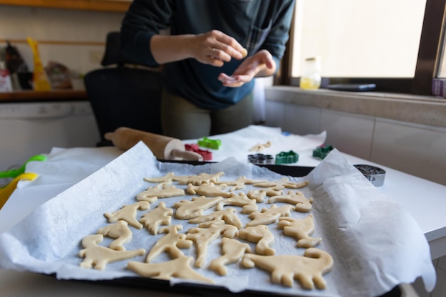 Een vrouw die koekjes bakt in de vorm van dinosaurussen op de bakplaat