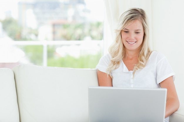 Een vrouw die lacht als ze naar het scherm van de laptop kijkt die ze gebruikt