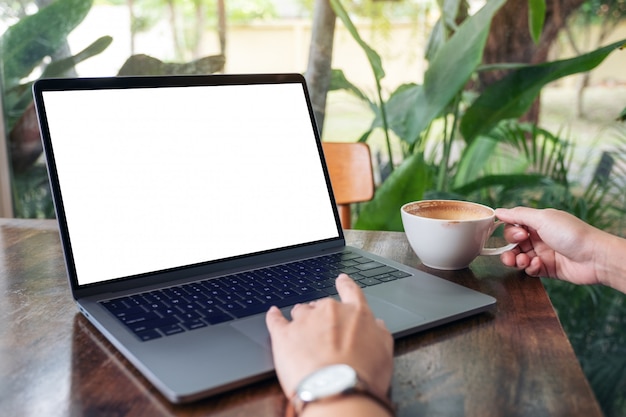 een vrouw die laptop-touchpad gebruikt en aanraakt met een leeg wit bureaubladscherm terwijl ze koffie drinkt