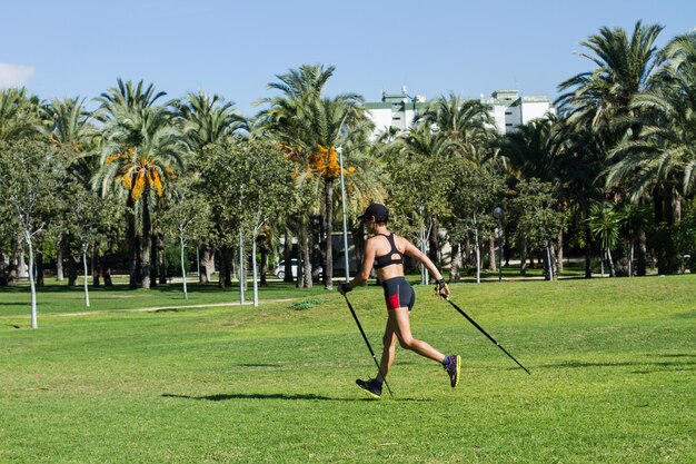 Een vrouw die nordic walking doet in het park