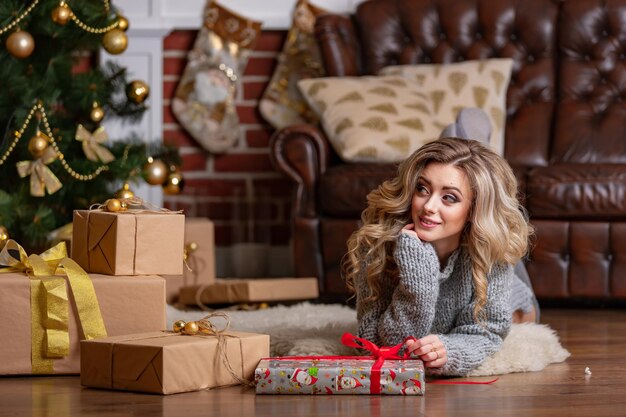 Een vrouw die op de vloer ligt naast een kerstboom