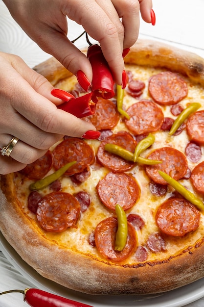 Een vrouw die pepperoni op een pizza legt