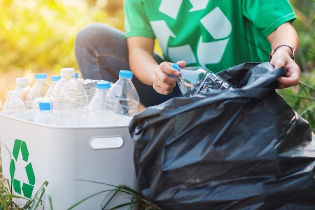 Foto een vrouw die plastic afvalflessen oppakt in een doos en een plastic zak voor recyclingconcept