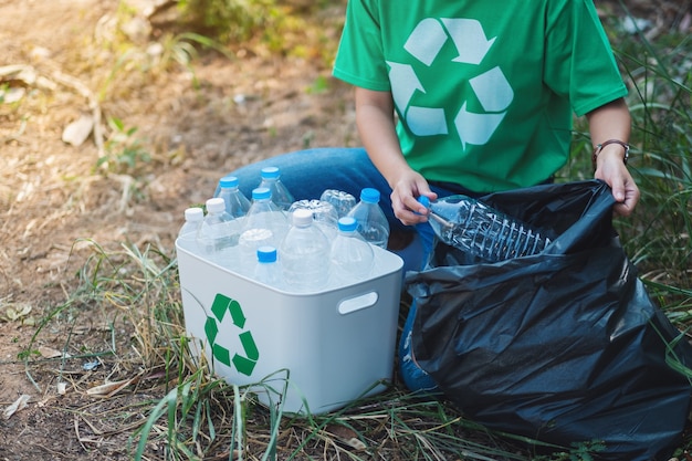 Foto een vrouw die plastic afvalflessen oppakt in een doos en zak voor recyclingconcept