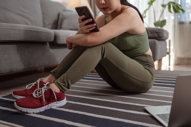 Een vrouw die rust en verfrist na het sporten en het gebruik van sociale media op de smartphone