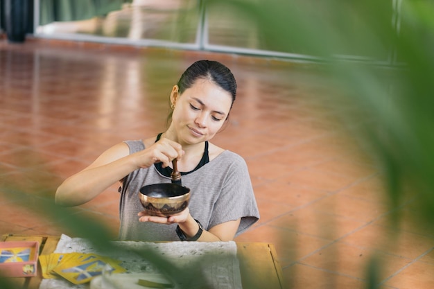 Foto een vrouw die spirituele therapie uitvoert, een kom vasthoudt en klankgenezing beoefent