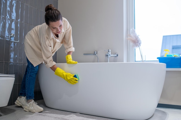 Een vrouw die thuis schoonmaakt en de badkamer desinfecteert