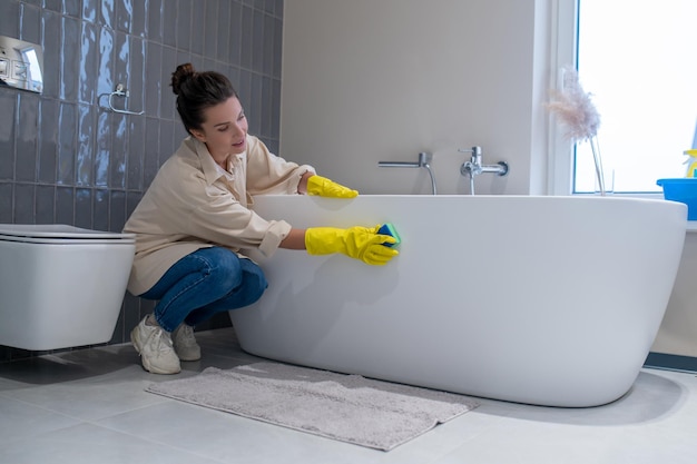 Een vrouw die thuis schoonmaakt en de badkamer desinfecteert