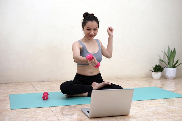 Een vrouw die thuis yoga doet met laptop