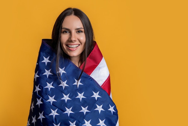 Een vrouw die trots de Amerikaanse vlag vasthoudt, kopieert een ruimtebanner, een vrouw met de Amerikaanse vlag, een symbool van kracht en vrijheid, een vrouw gewikkeld in de Amerikaanse vlag.