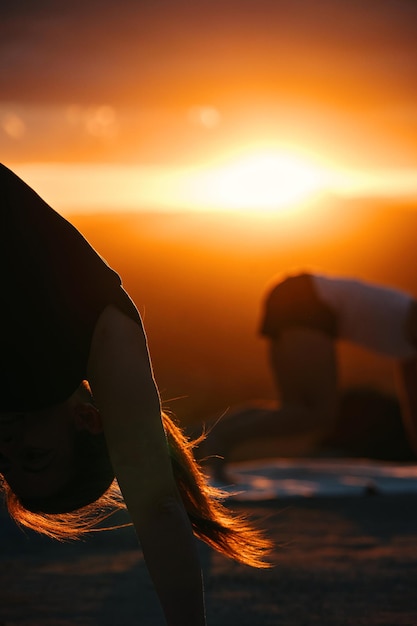 Een vrouw die yoga doet voor een zonsondergang