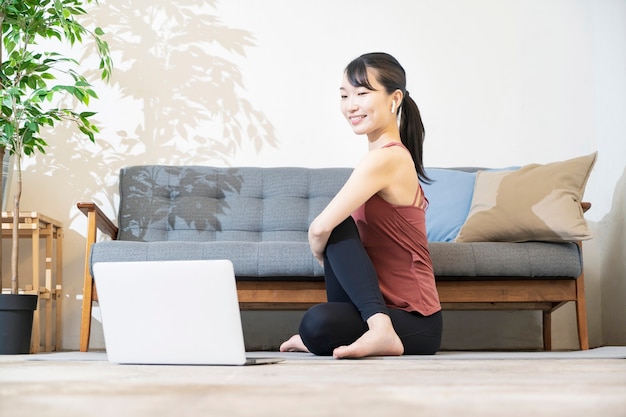 Een vrouw doet yoga terwijl ze naar het computerscherm in de kamer kijkt