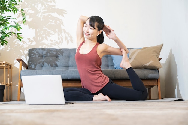 Een vrouw doet yoga terwijl ze naar het computerscherm in de kamer kijkt