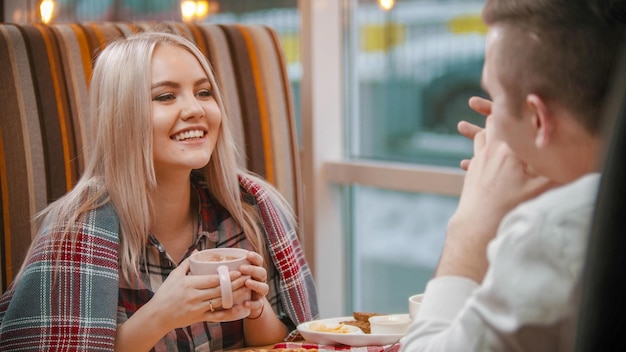 Een vrouw drinkt koffie en praat met haar vriendje in café