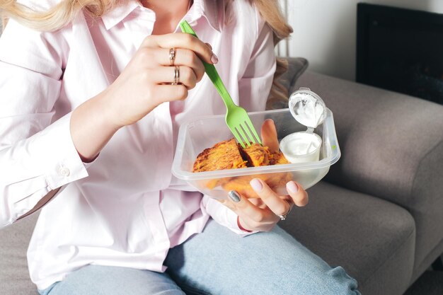 Een vrouw eet een maaltijd uit een container met voedsel.