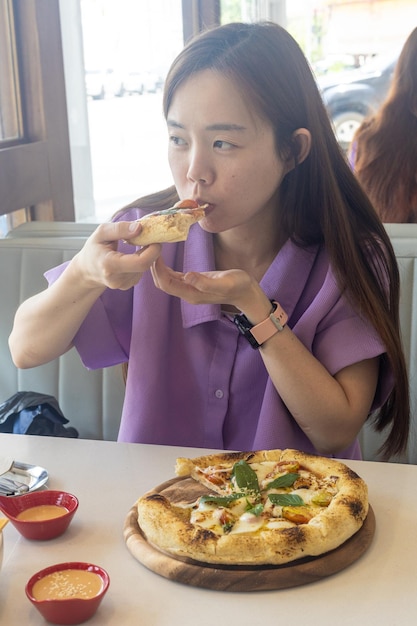 Een vrouw eet een pizza met haar handen.