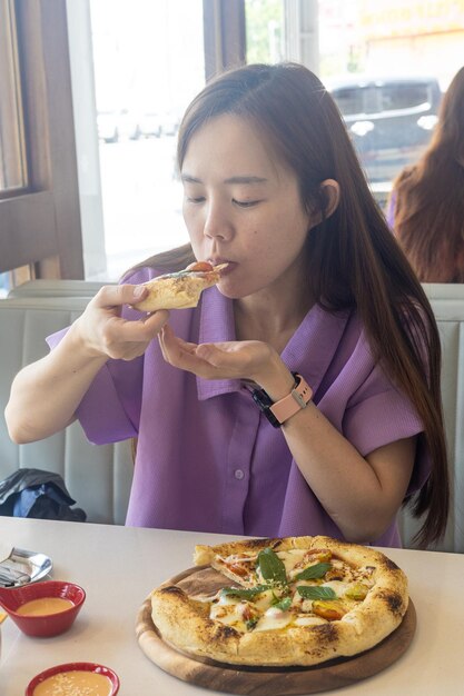 Een vrouw eet een pizza met haar handen.