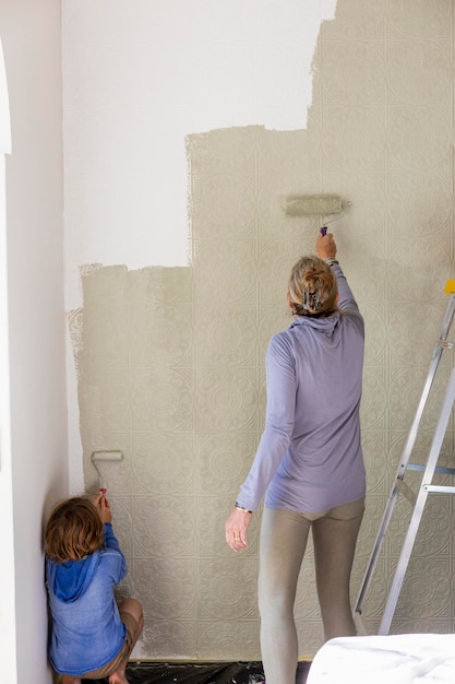 Een vrouw en een achtjarige jongen die een kamer verfraaien met het schilderen van muren