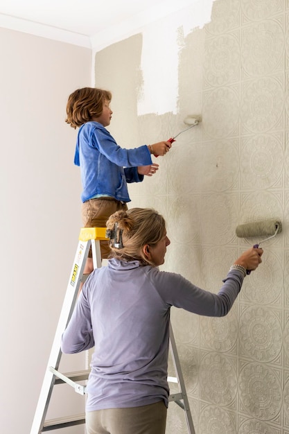 Een vrouw en een achtjarige jongen die een kamer verfraaien met het schilderen van muren