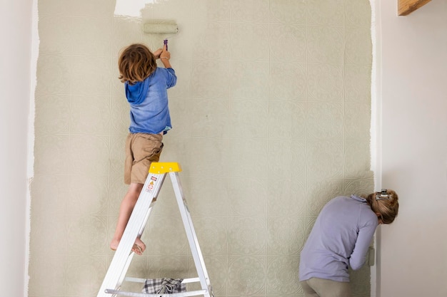 Een vrouw en een achtjarige jongen die een kamer verfraaien met het schilderen van muren