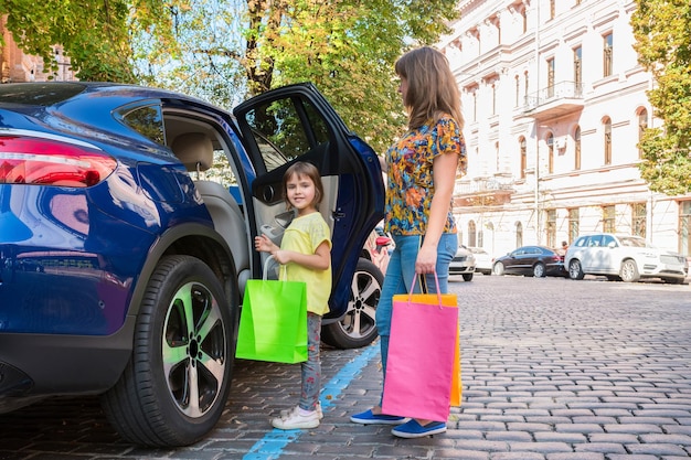 Een vrouw en een meisje staan met aankopen in de buurt van een auto