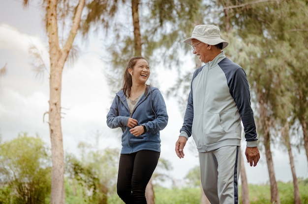 Een vrouw en opa lopen joggen op straat in het park Grandfather talk