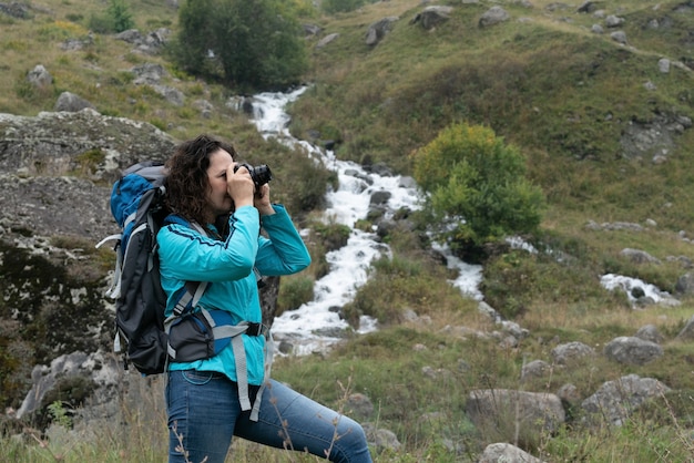 Foto een vrouw fotografeert het landschap in de bergen.