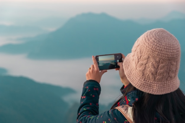 Een vrouw fotograferen met een smartphone uitzicht op de bergen en de ochtendzon