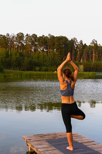 Een vrouw gaat sporten op het meer in de natuur. Het concept van fysieke activiteit in de natuur.