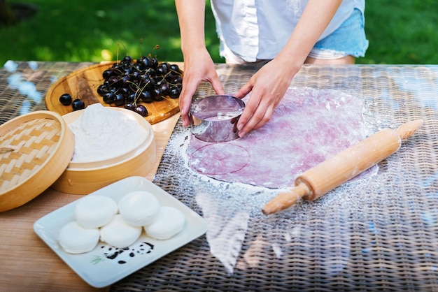 Een vrouw gebruikt een rolspeld op een tafel om voedsel voor te bereiden mochi aziatisch dessert