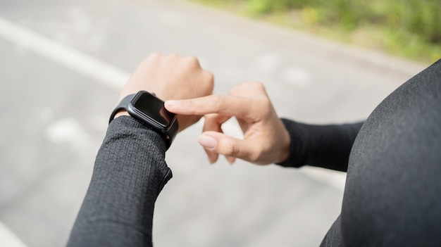 Een vrouw gebruikt een tracker op haar arm, een slim horloge voor sporttreinen in sportkleding