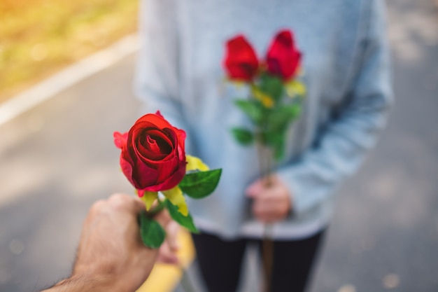 Een vrouw geeft op Valentijnsdag een roodroze bloem aan haar vriendje