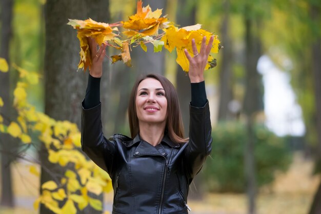 Een vrouw gooit herfstbladeren